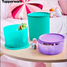 three plastic containers sitting on top of a wooden table next to a pink and blue umbrella