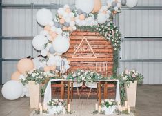 a table with balloons and flowers on it in front of a wooden backdrop at a wedding