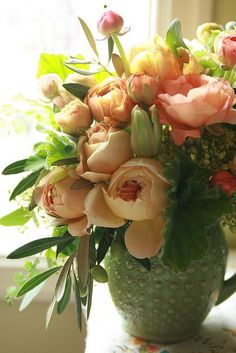 a vase filled with lots of flowers sitting on top of a table next to a window