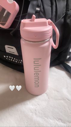 a pink water bottle sitting next to a backpack