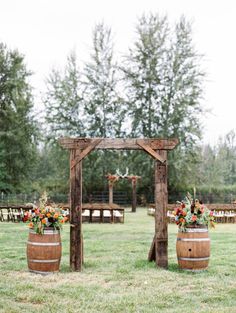 an outdoor ceremony setup with wooden barrels and flowers