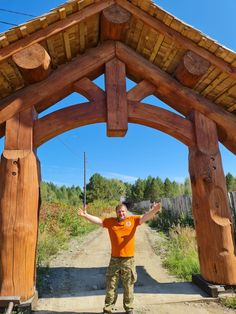 a man standing in front of a wooden structure with his arms out and hands up