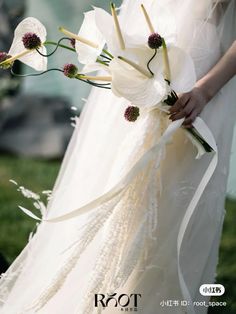 a woman in a white dress holding a bouquet with flowers on it's side