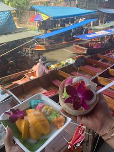 a person holding up a plate with fruit on it in front of other boats and people