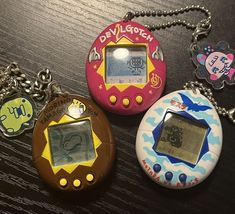 three electronic devices are on a table with keychains attached to the keys and chain