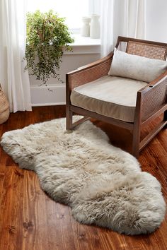 a white sheepskin rug is on the floor next to a chair and potted plant