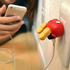 a woman holding a cell phone next to a plugged in charger with an angry bird on it