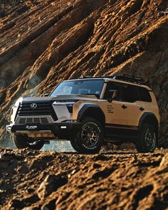 a white and black suv parked on the side of a rocky hill next to a mountain