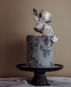 a black and white cake with flowers on it sitting on a table next to a wall