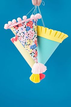 a hand holding a colorful kite with tassels hanging from it's side