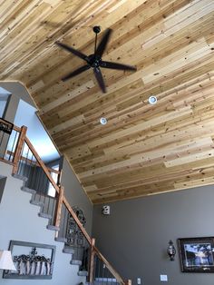 a ceiling fan mounted to the side of a wooden wall in a living room with stairs