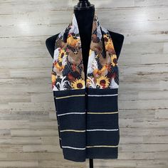 a black and white scarf with sunflowers on it sitting on a mannequin