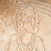 an ancient egyptian relief depicting a woman with a bird on her shoulder and headdress