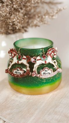 a green glass candle holder with two horses on it