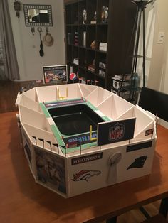 a cardboard model of a football stadium on top of a wooden table in a living room