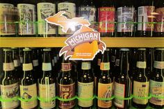 several bottles of beer are on display in a liquor store, with the michigan state sticker above them