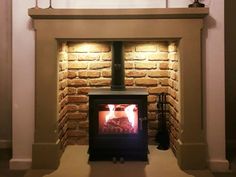 a brick fireplace with a wood burning stove in the center and lights on either side