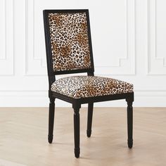 a leopard print chair sitting on top of a hard wood floor next to a white wall