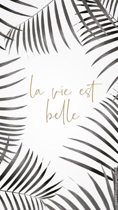 the words la vie est belie written in gold on a white background with palm leaves