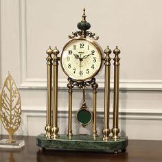 a clock sitting on top of a wooden table next to a gold trophy and an ornament