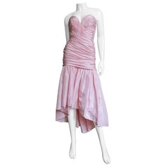 A great pink silk high low dress from Vicky Tiel. It has a drop waist horizontally ruched boned bustier bodice onto which is gathered a full skirt knee length in the front, ankle length in the back. The dress has a side zipper and is fully lined in pink silk. Fits sizes Small, Medium. Marked French size 36. Bust 34" Waist 27" Hips Open Length 32-46" Pink Silk Strapless Dress For Gala, Pink Formal Corset Dress With Ruched Bodice, Pink Strapless Ruched Dress For Formal Occasions, Pink Corset Dress With Ruched Bodice For Cocktail, Pink Ruched Silk Evening Dress, Pink Fitted Silk Strapless Dress, Pink Taffeta Cocktail Dress, Pink Ruched Evening Dress With Sweetheart Neckline, 1990s Clothes