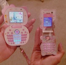 someone holding two cell phones in their hands with hello kitty stickers on the screen