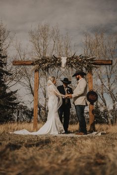 a bride and groom are standing under an arch at their wedding ceremony in the woods