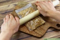 a person rolling up some food on a wooden board with a rolling pin and plastic bag