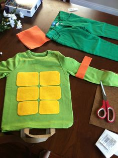 a child's green shirt with yellow squares on it and scissors next to it