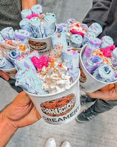 two people holding up cups filled with ice cream