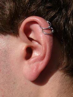 a close up of a person's ear with a ring attached to the side