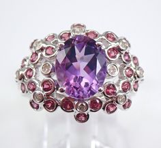 14K White Gold Diamond, Garnet and Amethyst Unique Engagement Ring. This ring is set with one genuine Oval Amethyst in the center, thirty Round Rhodolite Garnets and ten natural Round Brilliant Diamonds. These diamonds are H color, SI/I1 clarity and weigh a total of .10 carat. The Garnets are a beautiful berry color and weigh a total of .45 carat.  The center Amethyst measures 10 X 8 mm and weighs 2 1/4 carats. This ring is solid 14KT White Gold, weighs 5.1 grams and is a finger size 8, which is resizable free of charge (please inquire about sizing with the finger size you need). The ring will be accompanied by an appraisal by a GIA Certified Diamond Grader with the retail replacement value of $2,295.00. I will ship this ring promptly in a gift box. What a stunning piece to add to any jewe Amethyst And Garnet, Berry Color, Unique Engagement Ring, Dome Ring, Amethyst Gem, Engagement Ring Sizes, Purple Band, Garnet Ring, Ring Pictures