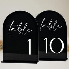 two black table numbers with white ink on them