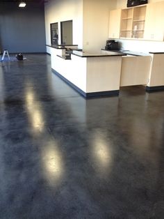 an empty room with black floors and white counters in the center is seen from across the room