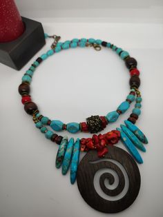 Beautiful ethnic style choker necklace, handmade with various materials: howlite, coral, jasper, hematite, wood. The central element of the necklace is a large pendant made of dark walnut-coloured cut-out wood. The turquoise blue of the jasper and the red of the coral contrast with each other and create a beautiful color combination. The necklace is double stranded, made up of different pearls and shells that create intersections of beautiful shapes and colors. The necklace is rigid but at the same time adheres perfectly to the neck and has an adjustable closure with a 7 cm extension. The necklace is very showy and colourful, in the colors of blue, red and brown, it is reminiscent of summer, the sea...suitable for a low-cut dress for a special occasion. It is a unique design created by me Traditional Turquoise Choker Necklace, Turquoise Wooden Beads Necklace For Festivals, Spiritual Turquoise Necklaces With Wooden Beads, Adjustable Bohemian Red Coral Necklace, Spiritual Turquoise Necklace With Wooden Beads, Handmade Turquoise Necklace With Red Coral, Bohemian Turquoise Necklace With Red Coral For Gift, Bohemian Turquoise Necklace With Red Coral, Traditional Turquoise Necklace With Wooden Beads