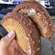 a person holding two waffles with chocolate frosting