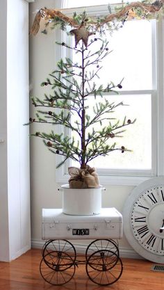 a small christmas tree sitting on top of a wooden cart next to a large window