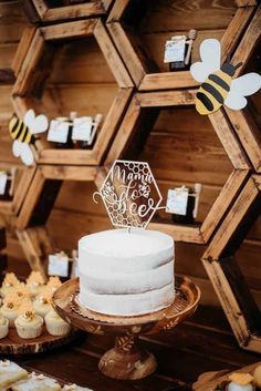 a white cake sitting on top of a table next to cupcakes and honeycombs