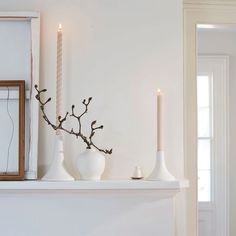 a white mantle with candles and vases on it