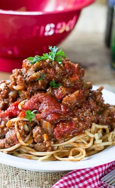 spaghetti with meat sauce and parsley on a plate next to a bottle of wine