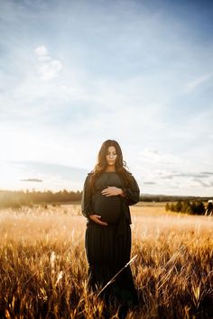 a pregnant woman standing in the middle of a field with her belly wrapped around her waist