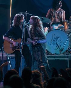 two women on stage singing and playing guitar