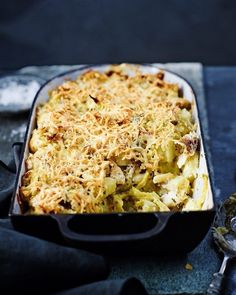 a casserole dish filled with macaroni and cheese next to a spoon