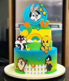 a three tiered cake with cartoon characters on the front and sides, sitting on top of a table