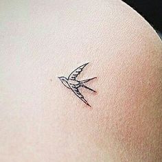 a small tattoo on the back of a woman's left arm, with a bird flying above it