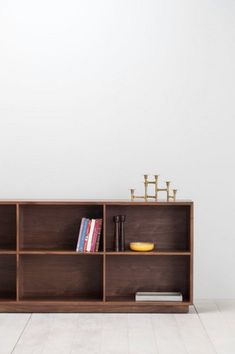 a book shelf with books and other items on it in front of a white wall