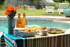 a table with food and drinks near a swimming pool