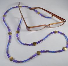 Beautiful 34" purple beaded eyeglass lanyard made with glass, pewter gold plated beads. Beads range from 4mm to 12mm and are various shapes including round, square and button. Rubber ends with gold ball to hold lanyard on glasses. This would make a lovely gift for a person who wears reading glasses and misplaces them often! Purple Glass Beaded Necklaces With Round Beads, Adjustable Gold Nickel-free Beaded Necklace, Purple Glass Beaded Necklace With Round Beads, Adjustable Round Beaded Necklace With Gold Beads, Adjustable Gold Beaded Necklaces Nickel Free, Adjustable Gold Metal Beads, Gold Adjustable Single Strand Glasses Chain, Adjustable Gold Beaded Necklace Nickel Free, Gold Single Strand Adjustable Glasses Chain