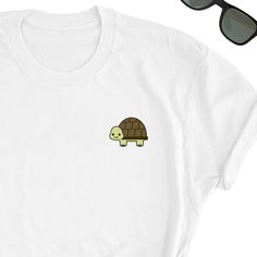 We have express delivery for our shirts! 📦⚡.  From cart to door in just 2-3 days, only for 3.5 USD extra.  You can find the express delivery option in the cart. Turtle Shirt, Cute Turtle Tee Shirt, Turtle Icon Tee Shirt, Turtle Lover T-Shirt, Turtle Cute Shirt Gift, Turtle Lover Friend UNISEX T-shirt Friends will love it! This t-shirt feels soft and lightweight, with the right amount of stretch. It's comfortable and flattering for both men and women.  * 100% cotton (heather colors contain polyester) * Fabric weight: 5 oz  * Shoulder-to-shoulder taping * Side-seamed Time for Delivery: * Processing & production time is 1-6 business days (usually 2-3 days). * U.S. Shipping time: 3-5 business days.  * International shipping time: 4-15 days. - Please note European customers: Some orders going Funny White Crew Neck Shirt, Cute White Crew Neck Shirt, White Basic T-shirt With Funny Print, White Crew Neck Shirt With Funny Print, Turtle Icon, Turtle Cute, Turtle Shirts, Cute Turtle, Cute Turtles