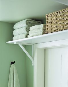 towels are stacked on top of the shelf above the door and in front of it is a towel rack